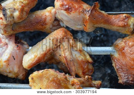 Closeup Of Some Meat Skewers Being Grilled In A Barbecue. Pieces Of Chicken Leg Meat Roasting On The