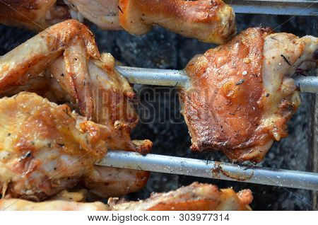 Closeup Of Some Meat Skewers Being Grilled In A Barbecue. Pieces Of Chicken Leg Meat Roasting On The