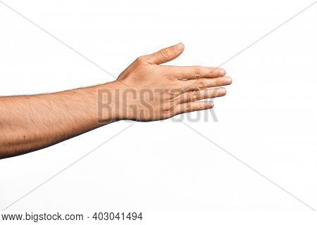 Hand of caucasian young man showing fingers over isolated white background stretching and reaching with open hand for handshake, showing back of the hand