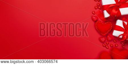 Valentines day greeting card template. Gift boxes, heart decor and candy sweets over red background. Top view flat lay with copy space