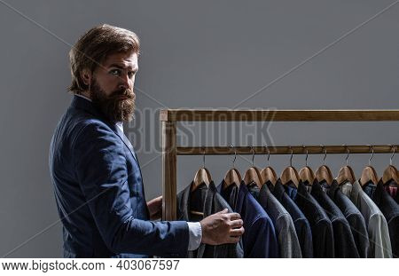 Tailor, Tailoring. Mens Suit, Tailor In His Workshop. Elegant Mans Suits Hanging In A Row. Luxury Me