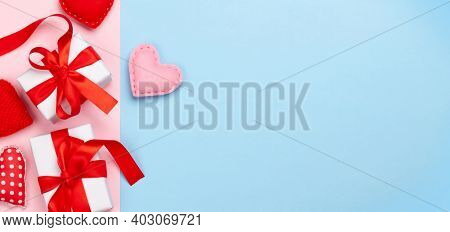 Valentines day greeting card template. Gift boxes and heart shaped decor over blue and pink background. Top view flat lay with copy space