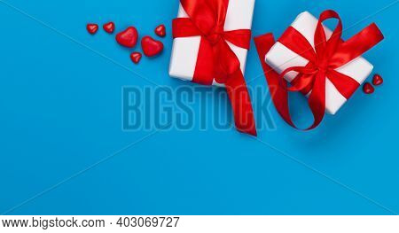 Valentines day greeting card template. Gift boxes and heart candy sweets over blue background. Top view flat lay with copy space
