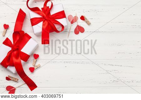 Valentines day greeting card template. Gift boxes and heart shaped decor on wooden background. Top view flat lay with copy space