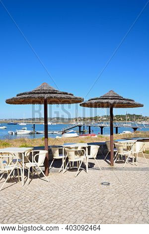 Alvor, Portugal - June 7, 2017 - Tables And Parasols On The Waterfront With Views Across The Estuary