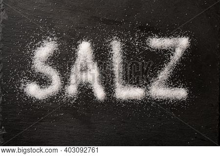 German Word Salz (meaning Salt) Written With Salt Crystals On A Dark Slate, High Angle View From Abo