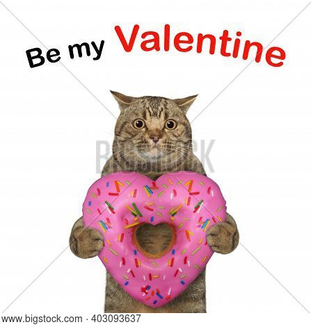 A Beige Cat Holds A Pink Heart Shaped Donut. Be My Valentine. White Background. Isolated.