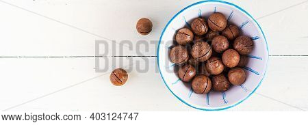 Organic Macadamia Nuts (macadamia Integrifolia) In Shell On Wooden White Table. Top View, Overhead, 