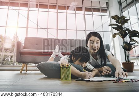 Mother And Daugther Is Coloring Book And Doing Homework On The Floor Together For Family Togethernes