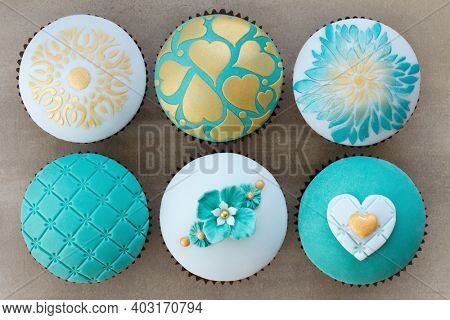 Wedding cupcakes decorated with teal and gold embossed fondant
