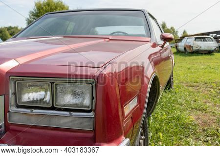 A Headlight Of A Red Retro Old Car Close Up In A Junk Yard, Nostalgia For The Old Days