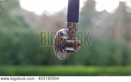 End Of Stethscope On Blue Rubber With Garden Backdrop - Copyspacae