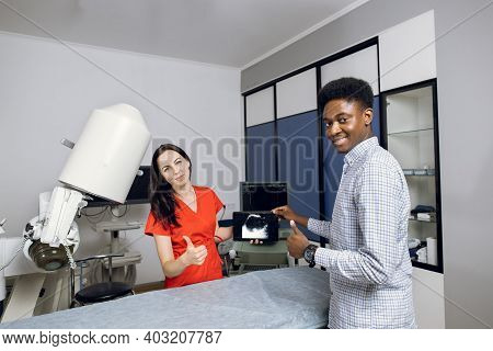 Happy Doctor And Patient In Modern Urology Clinic. Young Female Doctor And Her Male African Patient,