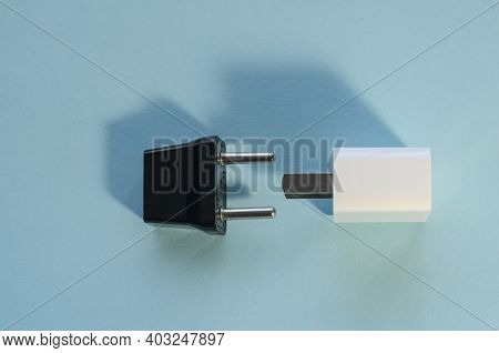 Black And White Interchangeable Dc And Ac Plugs. Wall Adapters For Usa And Europe On Blue Background