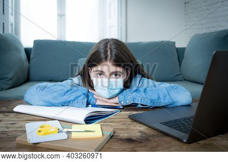 Coronavirus School Closures And Lockdown. Bored Kid With Face Mask Studying Online Class At Home
