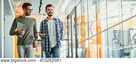 Two Male Co-workers Chatting And Walking In The Building