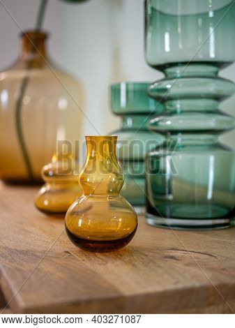 Transparent Yellow And Green Bottle Vases On Wooden Cupboard. Decoration Of Interior.