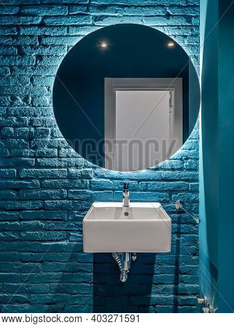 Bathroom With Blue Bricks Wall, Square Wash Basin And Round Mirror. Minimalist Interior.