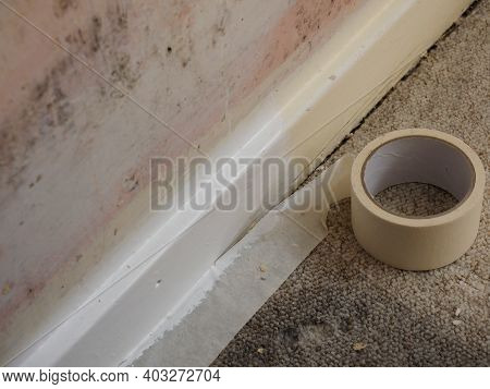 A Room Being Decorated Showing Bare Wall And Masking Tape Along Skirting Board