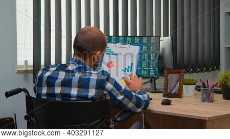 Handicapped Businessman Working With Financial Statistics Checking Graphs Sitting Immobilized In Whe