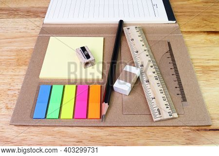 Note Paper Colour And Pencil Eraser Ruler With Book On Woodtable