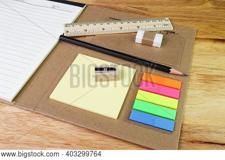 Note Paper Colour And Pencil Eraser Ruler With Book On Woodtable