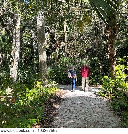 A Senior Couple Walking Along A Tropical Rock Pathway At Mckee Botanical Gardens In Vero Beach, Flor