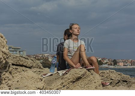 Bulgaria, Sozopol - 2018, 06 September: A Girl Sits With Her Back To A Guy With Her Eyes Closed, Blu