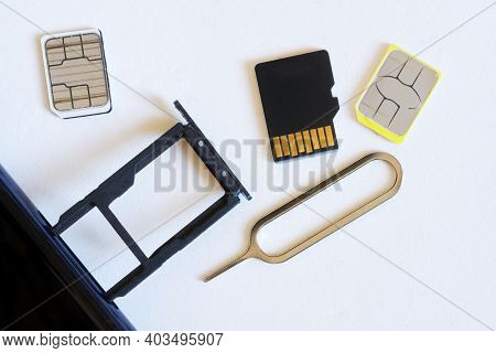 Two Miniature Nano Sim Cards, A Micro Sd Card And A Smartphone With An Extracted Tray Next To An Eje
