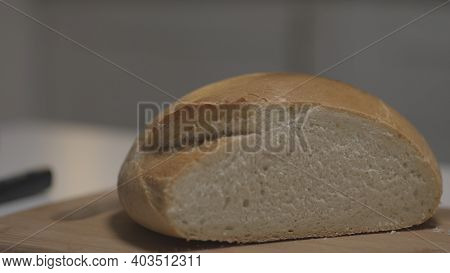 Close Up Of Female Hands Slicing White Bread In Slow Motion On A Wooden Board. Action. Cutting Fresh