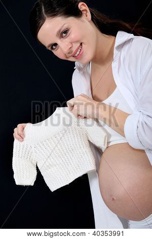 portrét krásné těhotné ženy držící handknit svetr