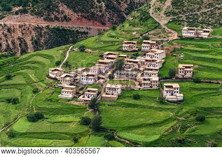 Tibetan Village Of White Traditional Houses And Its Fields On The Side Of A Mountain In Markam Count