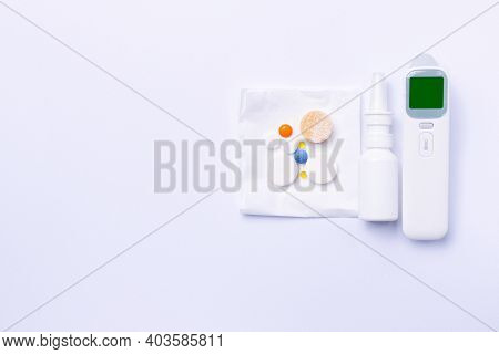 Non-contact Thermometer, Nasal Spray And Vitamins. Essential Remedy For Colds. White Background And 