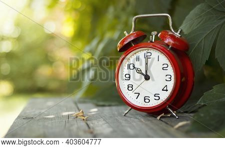Red Classic Alarm Clock In The Garden. Save Time, Daylight Saving Concept, Web Banner With Copy Spac