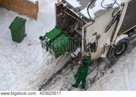 Trash Pickup In Winter - Garbage Collector Loading Garbage Truck, High Angle View