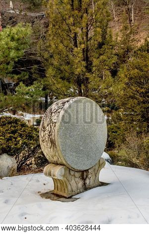 Decorative Stone Carved Korean Drum At Buddhist Temple In Front Of Evergreen Trees.