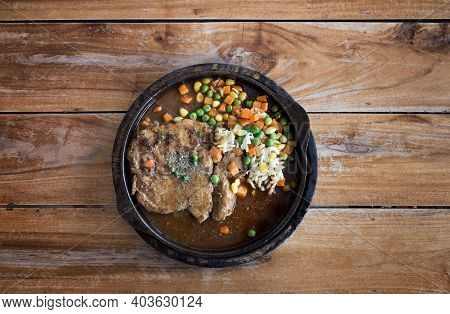 Pork Stake Serve On Hot Pan With Gravy Suace With Green Bean Carrot And Corn From Top View On Wood T