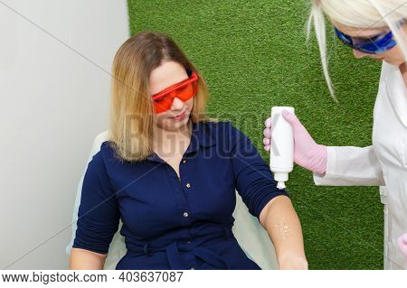 A Hair Removal Specialist Applies A Contact Gel For Laser Depilation On The Arm Of A Young Woman.