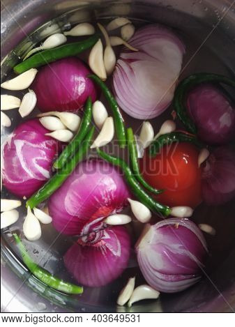 Cooking Ingredients Like Onion, Garlic, Green Chili, Tomato Are Washing Into Water.