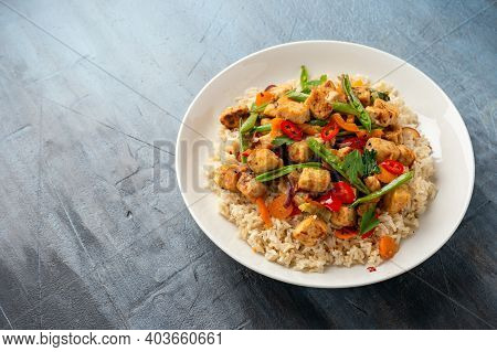 Vegetarian Meat Free Mycoprotein Pieces Vegetable Stir Fry, Brown Rice Served In White Plate