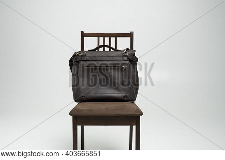 Brown Mens Shoulder Leather Bag For A Documents And Laptop On A Brown Chair With A White Background.