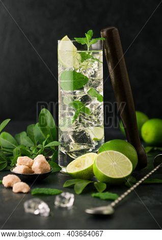 Highball Glass Of Mojito Cocktail With Ice Cubes,mint And Lime On Black Board With Spoon And Wooden 