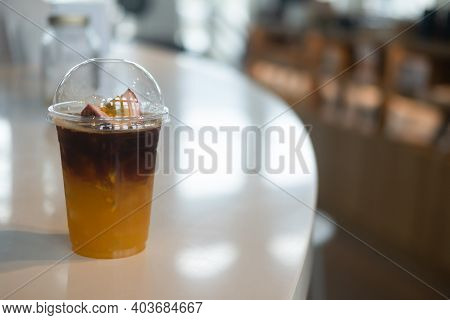 A Plastic Glass With A Cover Lid Of Iced Orange Juice And Passion Fruit Mix Black Cold Brew Coffee. 