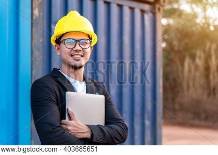 Happy Asian Yong Business Man Import And Export Goods Wear A Helmet Logitics Shipping At Container B