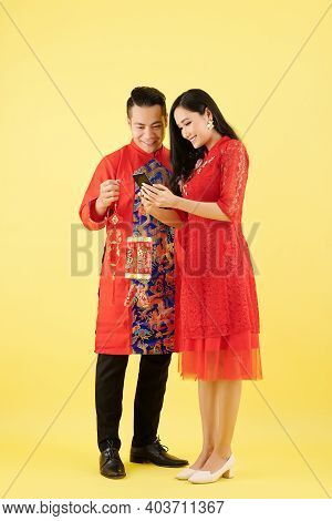 Young Couple With Wall Decorations Discussing What Else To Order Online For Lunar New Year Celebrati