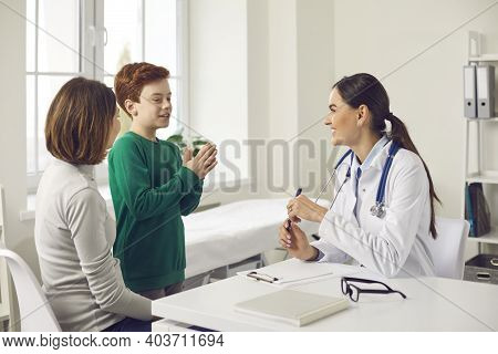 Happy Boy Patient Explaining Something During Checkup Visit To Woman Pediatrician