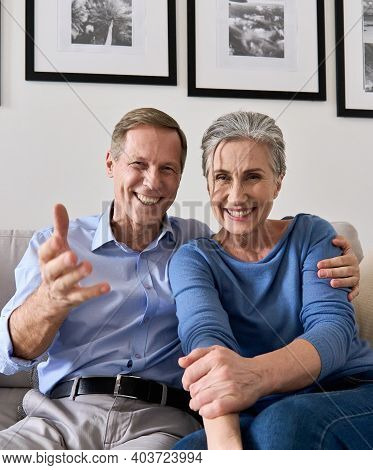 Happy Older Couple Greeting Family Making Online Video Call Talking To Web Cam. Middle Aged Old Gran