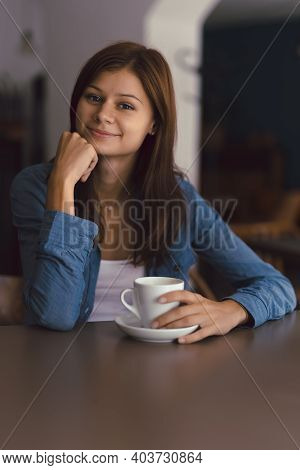 Photo Of Girl In Cafe With Cup Of Hot Chocolade Smiling And Looking To The Camera