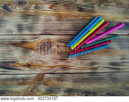 Colored Felt-tip Pens On A Background Of Burnt Wood.