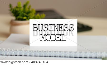 The Word Business Model Is Written On The White Card. Card On The Background Of Noteboook Bills And 